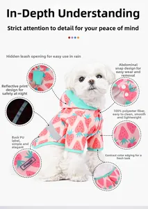Detail view showing strawberry print waterproof pet raincoat with reflective strips and snaps