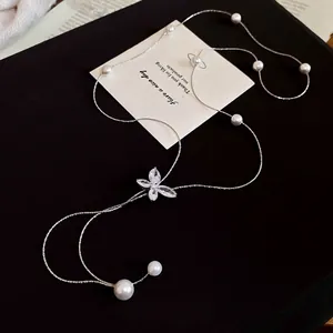 Elegant silver butterfly necklace with white pearls and sparkling zircons on black background