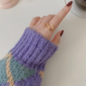 Close-up of a minimalist gold twisted curve ring and slim bands on a model hand