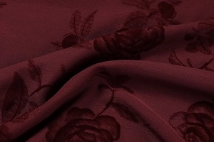 Detailed close-up of wine red jacquard fabric with elegant 3D rose floral patterns