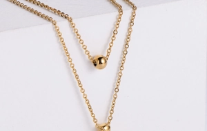 Detailed close-up of double-layered gold necklace featuring polished spherical bead pendants