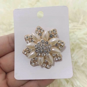 Elegant gold flower brooch with white faux pearls and crystals on a plush background