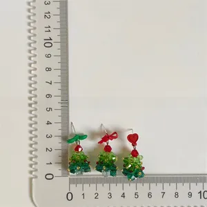 Size detail of beaded Christmas tree earrings with red bows and clear crystal beads