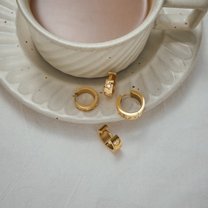 Close-up of gold heart and star earrings with cubic zirconia on a ceramic plate