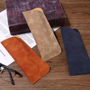 Premium soft faux suede glasses pouches in orange, beige, and navy blue on vintage desk
