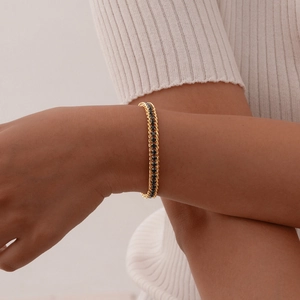 Detail of gold woven bracelet with black zircon inlay on a model's wrist