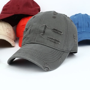 Close-up of distressed baseball caps in various colors with vintage ripped hole details