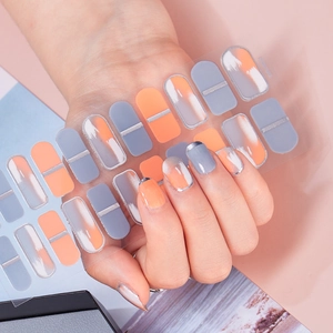 Detail of gradient orange and grey nail wraps with silver lines shown on model hand