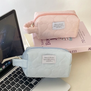 Quilted heart cosmetic bags in pink and blue colors on a laptop and books