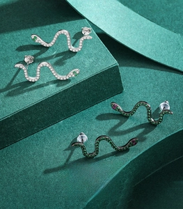 Macro detail of 925 silver snake stud earrings with zircon inlay in silver and black