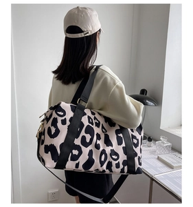 Detail of cow print travel bag with wide nylon handles and adjustable shoulder strap