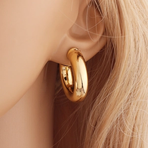 Détail de boucles d'oreilles créoles dorées épaisses de 28 mm avec finition polie