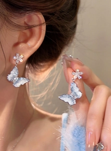 Detail view of icy blue butterfly earrings with sparkling crystal flower studs.