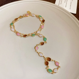Detail view of vintage gold chain bracelet and ring set with colorful oval rhinestones