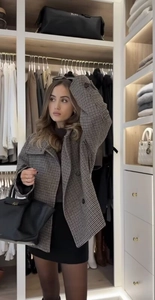 Detailed close-up of a double-breasted plaid coat with lapels in a luxury closet