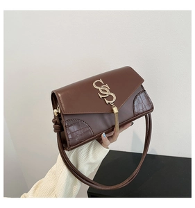 Detail of brown faux leather shoulder bag with gold S-logo and metal tassel fringe