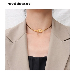 Detailed view of a gold belt buckle pendant on a sleek snake chain choker necklace