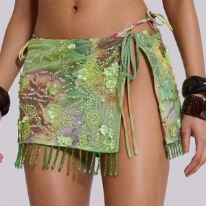 Macro detail of green mesh wrap skirt with floral sequins and beaded tassel fringe