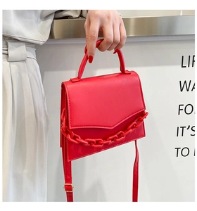 Detail of red square crossbody bag with chunky plastic chain and adjustable strap