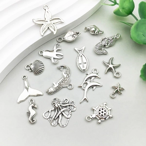 Antique silver sea charms including mermaid starfish and dolphin pendants on light background