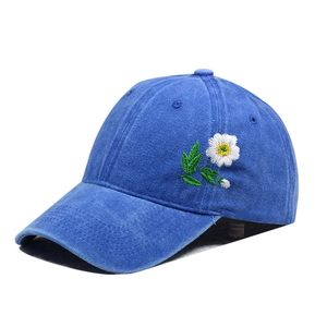 Detail of vintage washed blue baseball cap featuring delicate daisy embroidery on the side