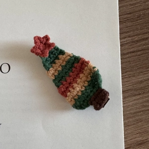Close-up of hand-knitted Christmas tree hair clip with festive red and green yarn