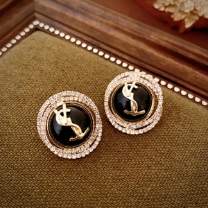 Macro detail of luxury vintage round stud earrings with gold lettering and faux diamonds