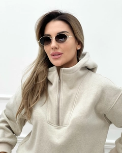 Dettaglio del tessuto della felpa beige con mezza zip e occhiali da sole ovali dorati