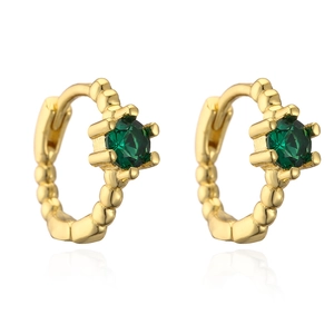 Dettaglio di orecchini a cerchio dorati ondulati con zircone verde e finitura testurizzata