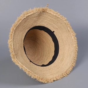Detailed top view of handmade raffia sun hat showing inner sweatband and fringe edges