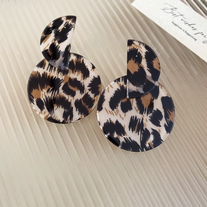 Macro shot of leopard print acrylic round earrings on a striped glass surface