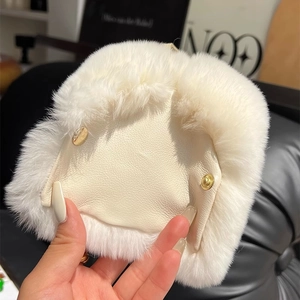 Detail of white rabbit fur and beige leather accessory with dual gold snap buttons