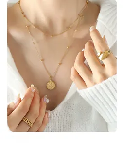 Close-up of double-layer gold necklace and rings on a model with a knit sweater
