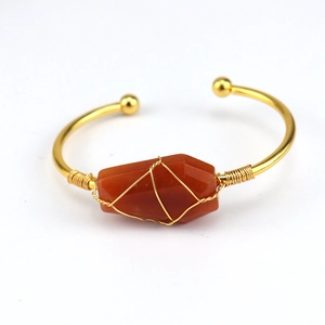 Handmade gold wire wrapped open bangle featuring a raw hexagonal carnelian gemstone