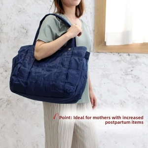 Quilted navy blue diaper bag showing spacious interior and wide shoulder strap comfort