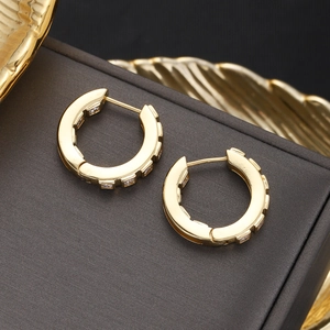 Detail of 18K gold plated hoop earrings with geometric zircons on textured display box