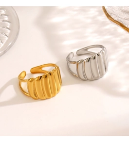 Detailed close-up of 18K gold and silver pleated shell rings on a glass surface