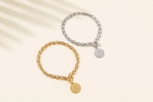 Detail of gold and silver chain bracelets with embossed coin pendants and T-bar clasps