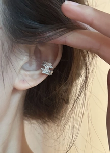 Detailed view of silver zircon leaf ear cuff worn on the cartilage without piercing
