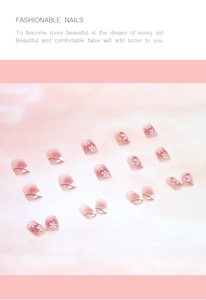 Close-up of pink gradient press-on nails with white flower patterns and gold accents