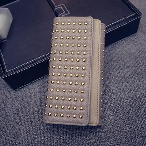 Dettaglio della pochette in pelle grigia con borchie dorate e finitura martellata elegante