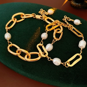 Detail of gold-plated chain bracelet featuring natural freshwater pearls on green velvet