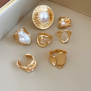 Detailed set of seven gold rings featuring baroque pearls and textured abstract patterns