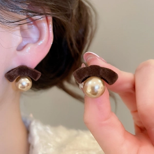 Detail of velvet bow earrings with gold pearls on ear to show texture and size