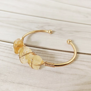 Detail of handmade gold wire-wrapped open cuff bracelet with natural raw yellow crystals