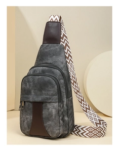 Detail of grey canvas crossbody bag with brown leather trim and geometric strap