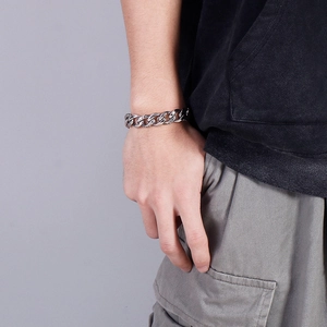 Detail of silver Cuban chain bracelet on male wrist with retro finish and vintage texture