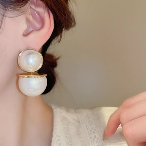 Gros plan d'élégantes boucles d'oreilles perles rouges et blanches sur l'oreille