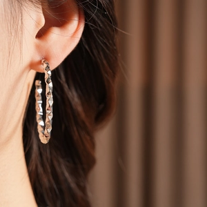 Close-up of model wearing silver geometric C-shape hoop earrings with a faceted design