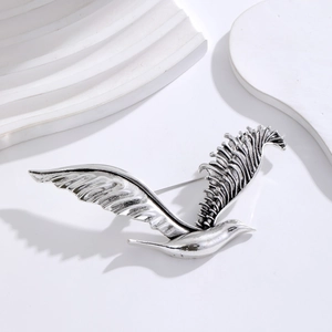 Detailed close-up of a silver seagull brooch with vintage texture on a white background